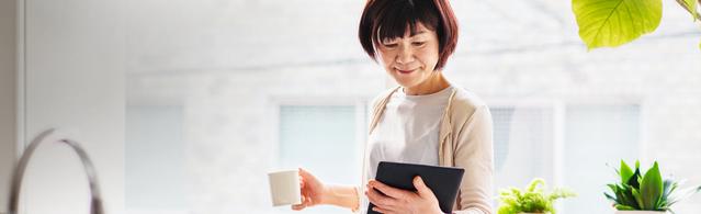 Woman holding coffee mug and tablet